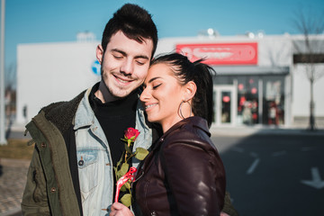 Woman hugs her boyfriend in Valentines day. Couple smiles and they are happy with their presents.
