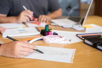 Two young professional Fashion designer colleagues working and project of drawing sketches for clothes in workplace with laptop, digital tablet and color charts, Fashion Designer Stylish Concept