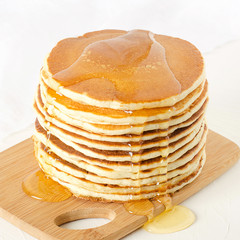 stack of pancakes on a yellow plate with honey