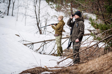 male and woman hunters ready to hunt, holding gun and walking in forest.