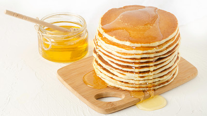 stack of pancakes on a yellow plate with honey