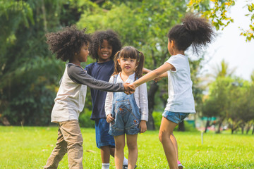 Group of kids have fun playing game holding hands in circle in the park
