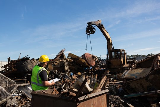 Worker monitoring the thrash being lifted by crane