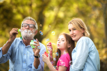 Naklejka premium Family and daughter blow soap bubbles in the garden. Soft focus concept.