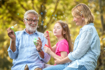 Family and daughter blow soap bubbles in the garden. Soft focus concept.