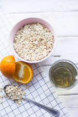 Healthy Breakfast, Sport, Fitness, Diet Concept. A bowl of oatmeal with a glass of green tean and fresh orange, white wood and plaid napkin as a background, top view