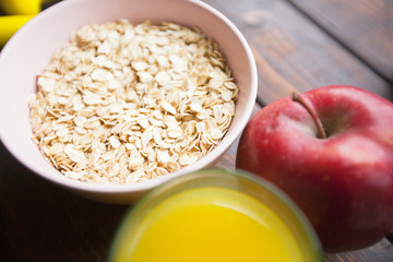 Healthy Breakfast, Sport, Fitness, Weight Loss, Diet Concept. Keeping fit with bowl of oatmeal, a fresh red apple and a glass of orange juice, dark wooden background