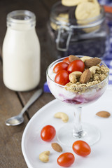 Yogurt with topping tomato almond cashew nut in wine glass with milk on wooden table.