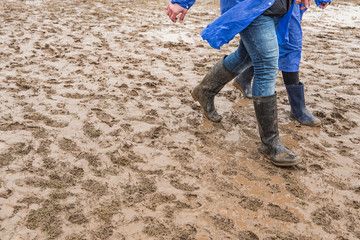 In rubber boots on dirt, at the festival