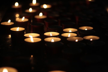 Votive candles glowing in the dark. Close up. Religion and faith icon or background.