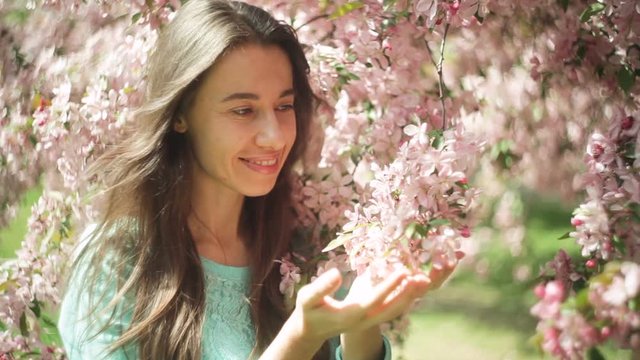 Beautiful lovely and young woman at the flowers of tree branches in spring