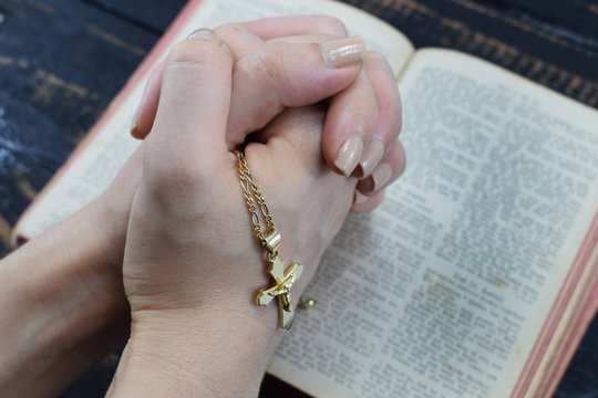 girl praying over the holy bible holding in her hand cross