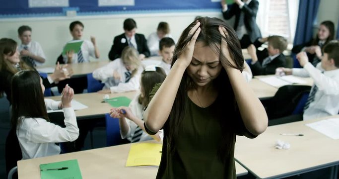 4k, Portrait of a helpless class teacher while students wreak havoc in the background. Slow motion.