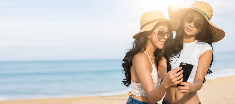 Couples lesbian or close friends are selfie or take photos for sharing in the online community During a vacation On the tropical beach with sunlight in travel concept,soft focus.