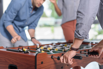 Businessmen playing table football in modern office