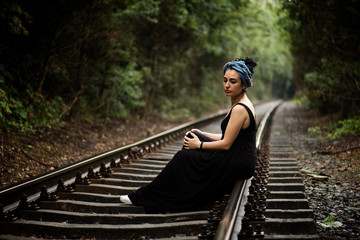 An attractive lonely young woman  with long black hair, wearing black long dress and turban, is...