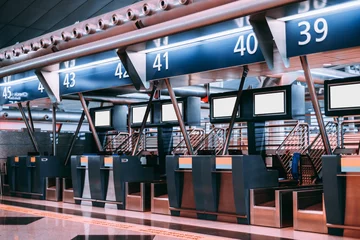Photo sur Plexiglas Aéroport Interior of check-in area in modern airport: luggage accept terminals with baggage handling belt conveyor systems, multiple blank white information LCD screen templates, indexed check-in desks