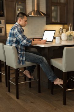 Man using laptop in kitchen