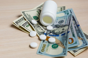 White pills of calcium vitamin supplement medical tablets on dollar banknote macro image