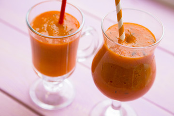Fruit and Vegetable Smoothie, Healthy Food, Diet Concept. Two glasses of orange smoothie with carrot and pumpkin on pink wooden background