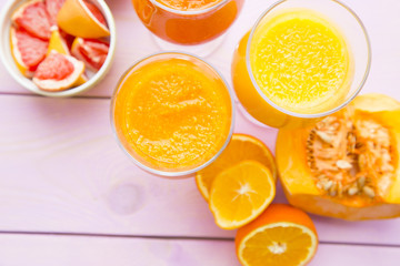 Healthy Food, Diet Concept. Fruit and Vegetable Smoothie assortment with fresh cut oranges, pumpkin and watermelon and red grapefruit on pink wooden background, top view