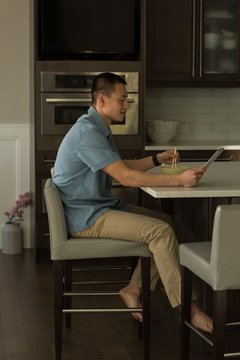 Man using digital tablet while having breakfast