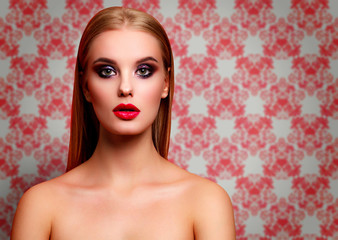 Closeup portrait of beautiful woman with bright make-up posing against a red wallpaper background