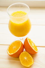 Fruit and Vegetable Smoothie, Healthy Food, Diet Concept. A glass of fresh citrus smoothie and cut oranges on a light wooden background