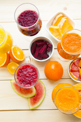 Healthy Food, Diet Concept. Fruit and Vegetable Smoothie assortment with fresh cut oranges, beetroot, pumpkin, mango and watermelon on light wooden background, top view