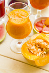 Healthy Food, Diet Concept. A glass of orange smoothie made of fruit and vegetables with a pice of pumpkin in a close up, light wooden background