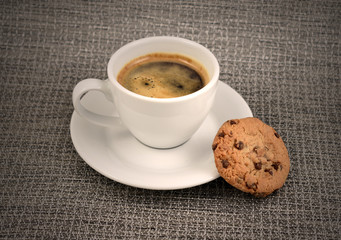 Chocolate cookie with coffee stock images. White cup of coffee with snack. Cup of coffee with cookie. Espresso with sweetness