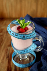 Strawberry protein cocktail decorated with berries and mint in an Irish mug wrapped into a blue measure tape. Sport nutrition concept