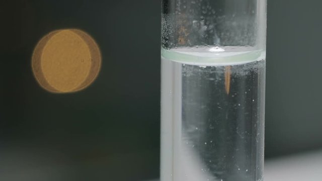 Chemical reaction in a glass vial. Determination of acidity. Reaction of acid and alkali. Effervescence. Scientific laboratory. Close-up. Mixing of pigment.