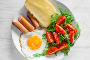 Fototapeta na wymiar Breakfast which includes eggs, sausages, salad and toast with cheese
