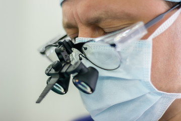 Surgeon wearing binocular loupes in operating room