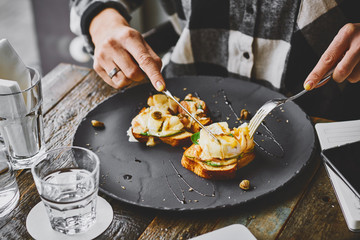Person eating eggs benedict at a cafe table