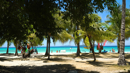 Tropical beach on the island Malcapuya, Palawan, Philippines. Beautiful tropical island with sand beach, palm trees. Tropical landscape: beach with palm trees. Seascape: Ocean, sky, sea. Travel