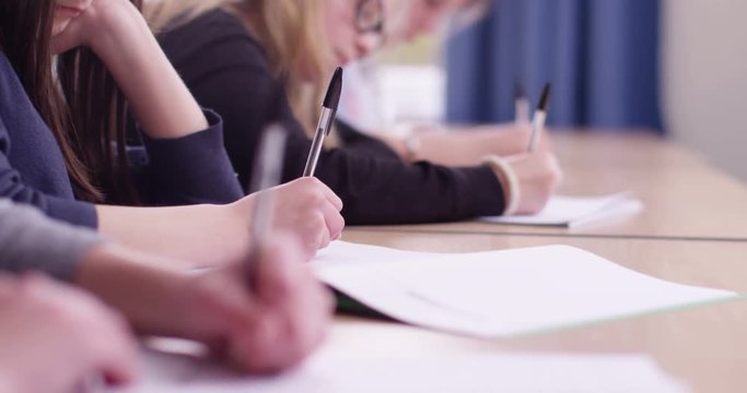 4k, Students in school uniform taking exam at desk in a classroom. Slow motion.