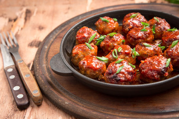 Meatballs in sweet and sour tomato sauce. Homemade roasted beef meatballs in cast-iron skillet