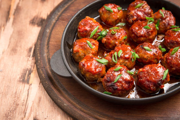 Meatballs in sweet and sour tomato sauce. Homemade roasted beef meatballs in cast-iron skillet
