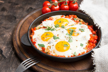 Tasty and Healthy Shakshuka in a Frying Pan. Fried eggs with tomatoes, bell pepper, vegetables and herbs. Middle eastern traditional dish.