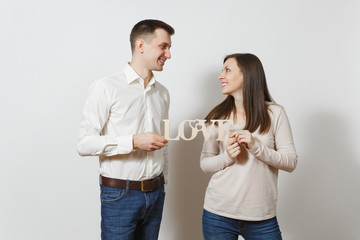 Young cute couple in love. Man and woman with wooden word Love isolated on white background. Copy space for advertisement. St. Valentine's Day International Women's Day birthday holiday concept.