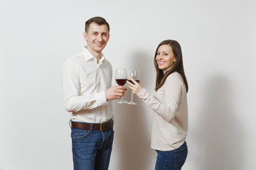 Young caucasian couple. Happy smiling man and woman in love in casual light clothes, jeans making toast, drinking from glasses of red wine isolated on white background. Copy space for advertisement.