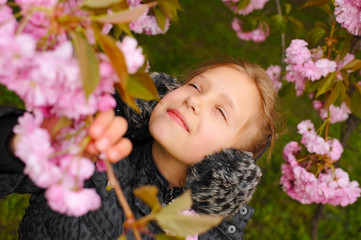 Fototapeta premium Young girl enjoys spring. She is resting at a tree with pink flowers