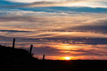 Sonnenuntergang auf Sylt, im Vordergrund die Silhouette eines Weidezauns