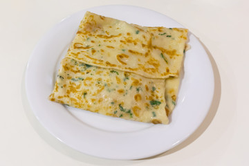 Russian pancake with filling on a white plate