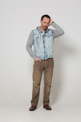 Handsome man in brown jeans standing on white background.