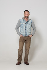 Fototapeta premium Cool guy in jeans sleeveless jacket and brown trousers. sexy man concept.
