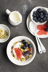 Seasonal healthy breakfast: yoghurt, chocolate granola, pink grapefruit, grapes, pistachios Top view Copy