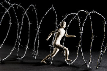 Man runs in barbed wire tunnel. Isolated on dark background. Studio Shoot.